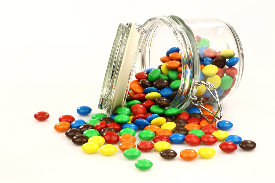 colorful sweets in a glass jar on a white background
